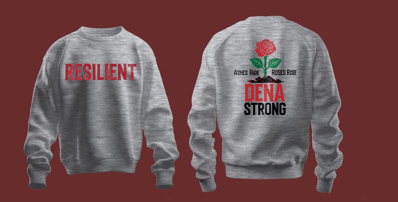 以下が含まれることがあります： 前面に赤い文字で「RESILIENT」と印刷され、背面に「ASHES FADE ROSES RISE DENA STRONG」というテキストと赤いバラと緑の葉が印刷された灰色のスウェットシャツです。