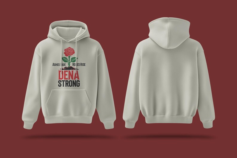 K&ouml;nnte beinhalten: Ein hellgrauer Hoodie mit einem roten Rosenmotiv und dem Text "Ashes Made Roses Rise Dena Strong". Der Hoodie hat eine Kapuze mit Kordelzug und eine K&auml;ngurutasche.