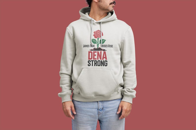 K&ouml;nnte beinhalten: Ein hellgrauer Hoodie mit einem Rosenmotiv und dem Text "Ashes Fade Roses Rise Dena Strong".