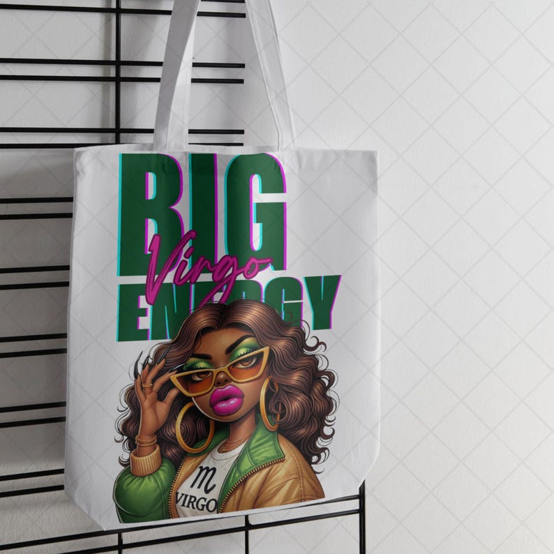 May include: White tote bag with a graphic of a woman wearing sunglasses and the text "BIG Virgo ENERGY". The woman has brown hair, gold hoop earrings, and pink lipstick. The text is in green and pink.