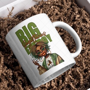 May include: White ceramic mug featuring a graphic of a woman with green-tinted sunglasses and the words "BIG Sagittarius ENERGY" in green. The woman is wearing a green jacket and gold hoop earrings. The mug is in a gift box with brown packing material.