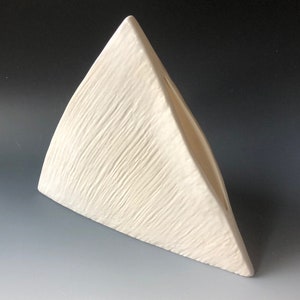 May include: White ceramic triangular vase with a textured surface.
