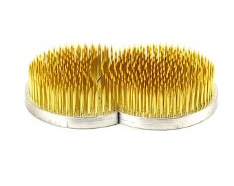 May include: A double-ended floral foam with a heart shape and gold-colored pins. The foam is designed for arranging flowers and other floral elements.