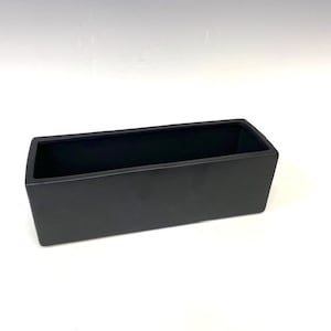 May include: A black rectangular ceramic planter with a smooth, matte finish. The planter is designed for indoor or outdoor use.