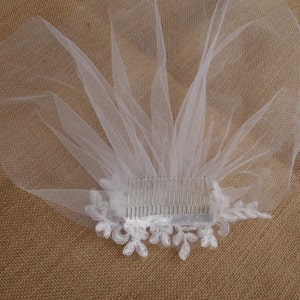 Peut inclure: Voile de mari&eacute;e blanc avec un peigne et une bordure en dentelle. Le voile est en tulle doux et pr&eacute;sente un motif floral d&eacute;licat.