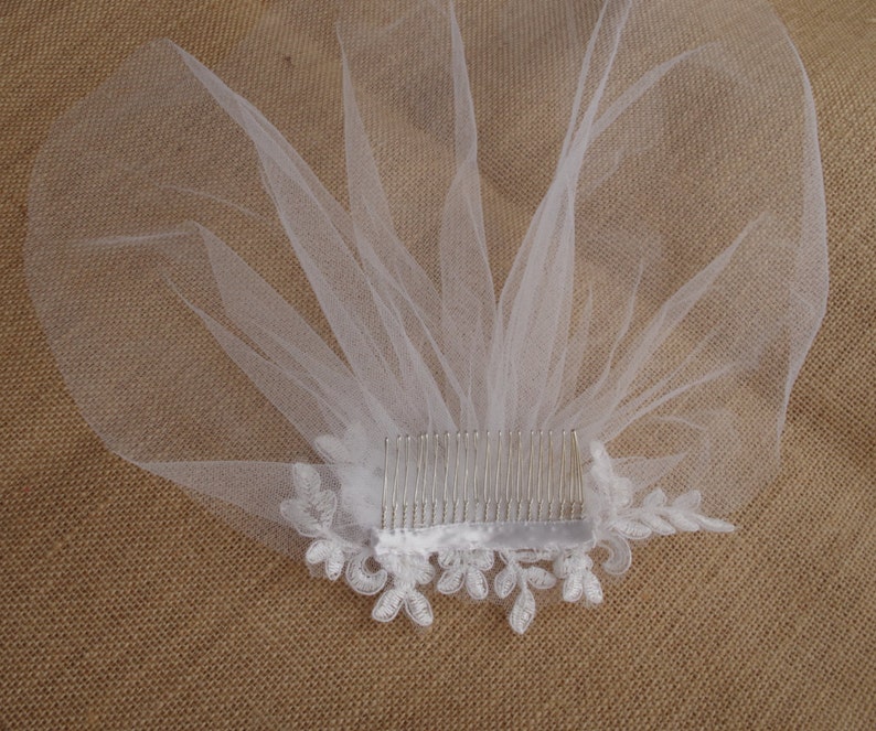Peut inclure: Voile de mari&eacute;e blanc avec un peigne et une bordure en dentelle. Le voile est en tulle doux et pr&eacute;sente un motif floral d&eacute;licat.