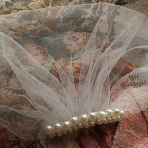 May include: A white tulle veil with a row of pearl beads sewn across the bottom edge.