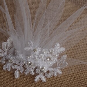 Peut inclure: Voile de mari&eacute;e blanc avec une d&eacute;licate bordure en dentelle et des embellissements de perles et de strass.