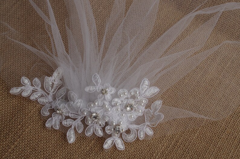 Peut inclure: Voile de mari&eacute;e blanc avec une d&eacute;licate bordure en dentelle et des embellissements de perles et de strass.