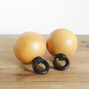 May include: Two wooden salt and pepper shakers with black metal rings. The shakers are round and have a light brown color.