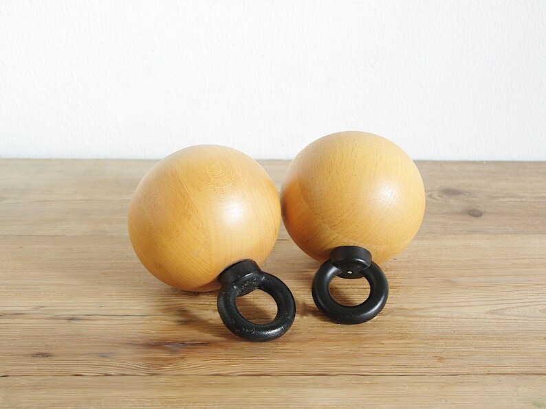 May include: Two wooden salt and pepper shakers with black metal rings. The shakers are round and have a light brown color.