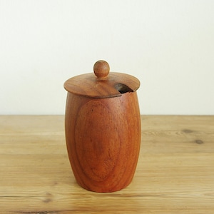 May include: A wooden jar with a lid and a small knob on top. The jar is a warm brown color and has a smooth, polished finish. The lid has a small opening. The jar is likely used for storing food items.