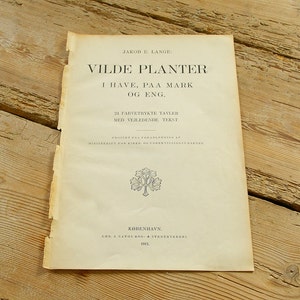 May include: A vintage book cover with the title "VILDE PLANTER" in black text. The book is about wild plants and features 24 color plates with descriptions. It was published in Copenhagen in 1913.