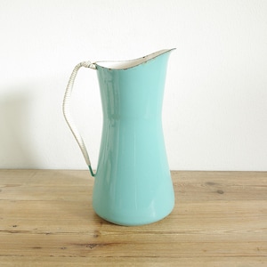 May include: A light blue enamel jug with a white rim and a white handle. The jug has a classic design and is perfect for serving drinks.