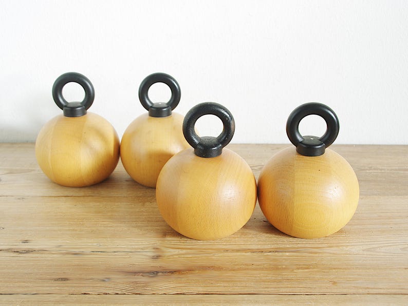 May include: Four wooden salt and pepper shakers with black handles. The shakers are round and have a light wood color.