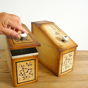 Könnte beinhalten: Zwei Holzkisten mit Blumendesigns und weißen Knöpfen. Die Kisten sind mit "Tee" und "Kaffee" beschriftet.