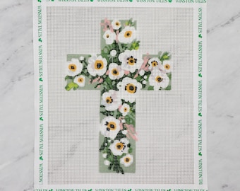 May include: A white cross with a floral design. The cross is surrounded by white flowers with pink centers and green leaves. The background is a light green color.
