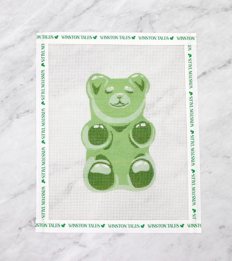 May include: Green gummy bear with closed eyes and a smile. The gummy bear is in a standing position with its arms and legs outstretched.