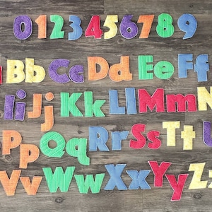 May include: Colorful fabric letters and numbers, including the alphabet from A to Z and the numbers 0 through 9. Each letter and number is a different color and has a stitched outline.