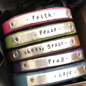 May include: Five leather bracelets with silver metal plates engraved with the words "faith", "peace", "choose grace", "pray", and "hope".