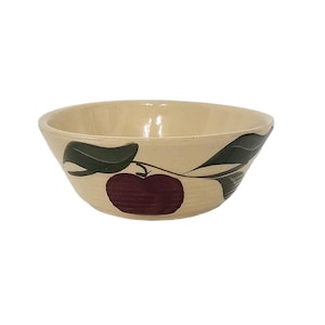 Puede incluir: Cuenco de cerámica color crema con un diseño de manzana pintado a mano. El cuenco presenta una manzana roja oscura con hojas y tallos verdes. El cuenco es redondo y tiene un borde ligeramente ensanchado, adecuado para servir.