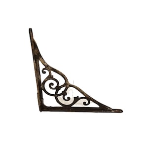 May include: A decorative, corner-shaped shelf bracket with an ornate, scrolled design. The bracket is made of dark brown metal with a distressed finish, and is designed to be mounted on a wall. The bracket is ideal for supporting shelves.