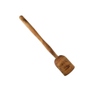 Puede incluir: Un mortero de madera con una cabeza redondeada y un mango largo y delgado. La herramienta de cocina es de madera de color marrón claro y está en ángulo diagonalmente sobre un fondo blanco. Se utiliza para mezclar ingredientes en cócteles.