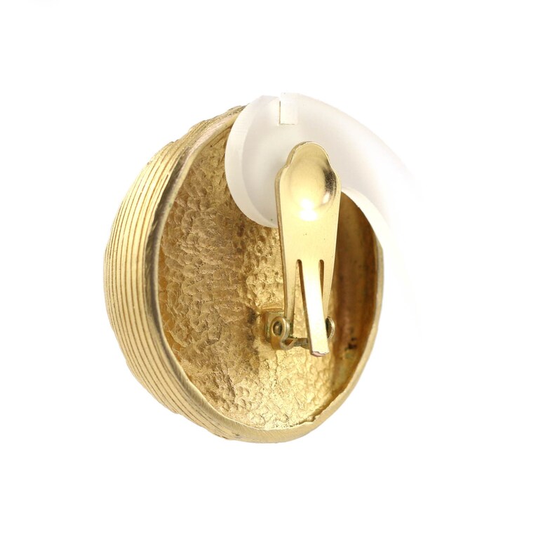 May include: Gold-toned clip-on earrings with a textured, round design. The earrings have a simple, classic style.