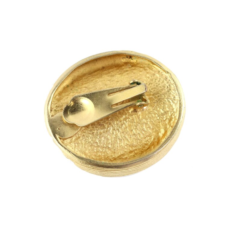 May include: Gold-toned clip-on earrings with a textured round design. The back of the earrings feature a gold-toned metal clasp.