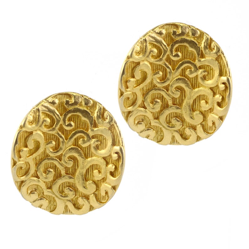 May include: A pair of gold-tone earrings with a circular design featuring a swirling pattern.