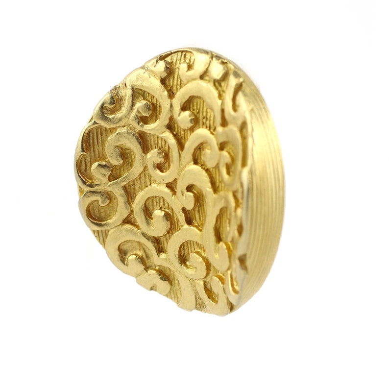 May include: A gold-colored ring with a detailed, swirling design. The ring is made of metal and has a smooth, polished finish.