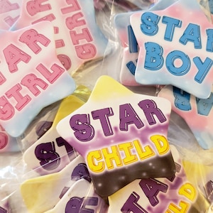 Könnte beinhalten: Eine Sammlung von sternförmigen Anstecknadeln mit verschiedenen Hintergrundfarben und Text. Die Anstecknadeln sagen "Star Girl", "Star Boy" und "Star Child".