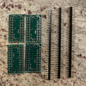 May include: Four green circuit boards with gold connectors and black text. The boards have the text "256/512 64/128" and "U24 v.3". Three rows of gold-plated pin headers are also shown.
