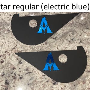 May include: Two black triangular-shaped decals with a blue "A" logo in the center. The logo is a stylized letter "A" with a bird silhouette inside. The decals are on a light gray granite countertop.