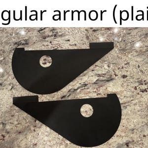 May include: Two black armor pieces with a circular hole in the center. The armor pieces are made of a flexible material and are designed to protect the wearer from injury.
