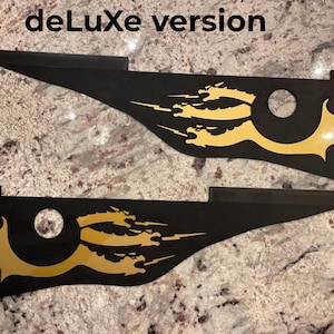 Op de afbeelding: Twee zwarte vinyl stickers met een gouden klauw ontwerp. De stickers hebben een uitgesneden cirkel in het midden. De tekst "deLuxe version" is zichtbaar bovenaan de afbeelding.