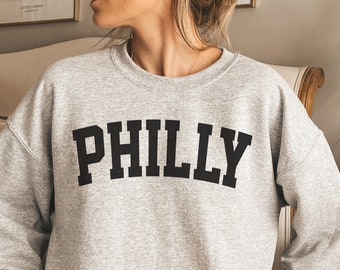 May include: A gray sweatshirt with the word "PHILLY" printed in black block letters.