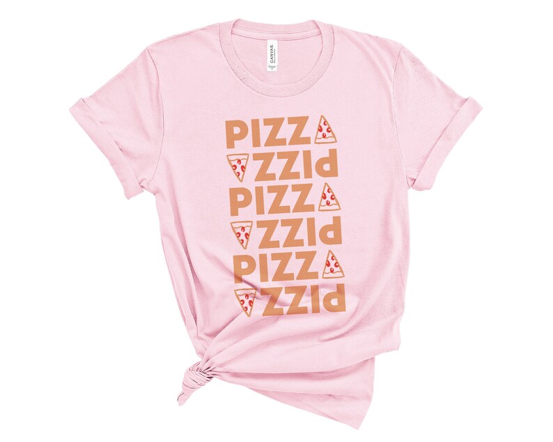 May include: A light pink t-shirt with rolled-up sleeves. The shirt features the word "PIZZA" stacked vertically five times in a brown color, with a pizza slice graphic next to each word. The shirt is knotted at the bottom.