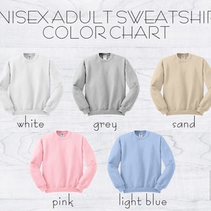 May include: A color chart for unisex adult sweatshirts. The sweatshirts are displayed in white, grey, sand, pink, and light blue. The text "UNISEX ADULT SWEATSHIRT COLOR CHART" is at the top of the image.