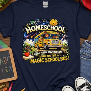 Op de afbeelding: Een marineblauw t-shirt met een afbeelding van een gele schoolbus en de tekst "HOMESCHOOL", "LEARNING ADVENTURE!" en "HOP ON THE MAGIC SCHOOL BUS!". Het ontwerp bevat een zon, een planeet, een raket, een appel en een open boek.