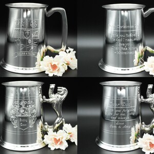 May include: Four silver pewter tankards with different engravings. The tankards have a lion head handle and a rounded base. The engravings include a coat of arms, a Christmas message, and a message to a father.