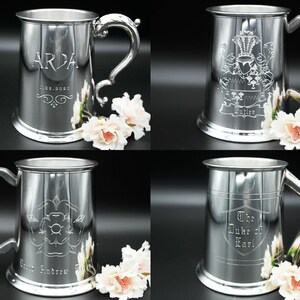 May include: Four silver pewter tankards with different engraved designs. The tankards have a rounded body, a handle, and a base. The designs include a crest, a rose, a name, and a title.