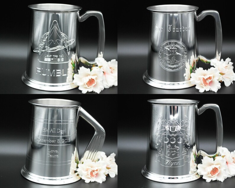 May include: Four silver pewter tankards with different engraved designs. The tankards have a rounded body and a handle. The designs include a crest, a ship, a crest with a dog, and a crest with a bird.
