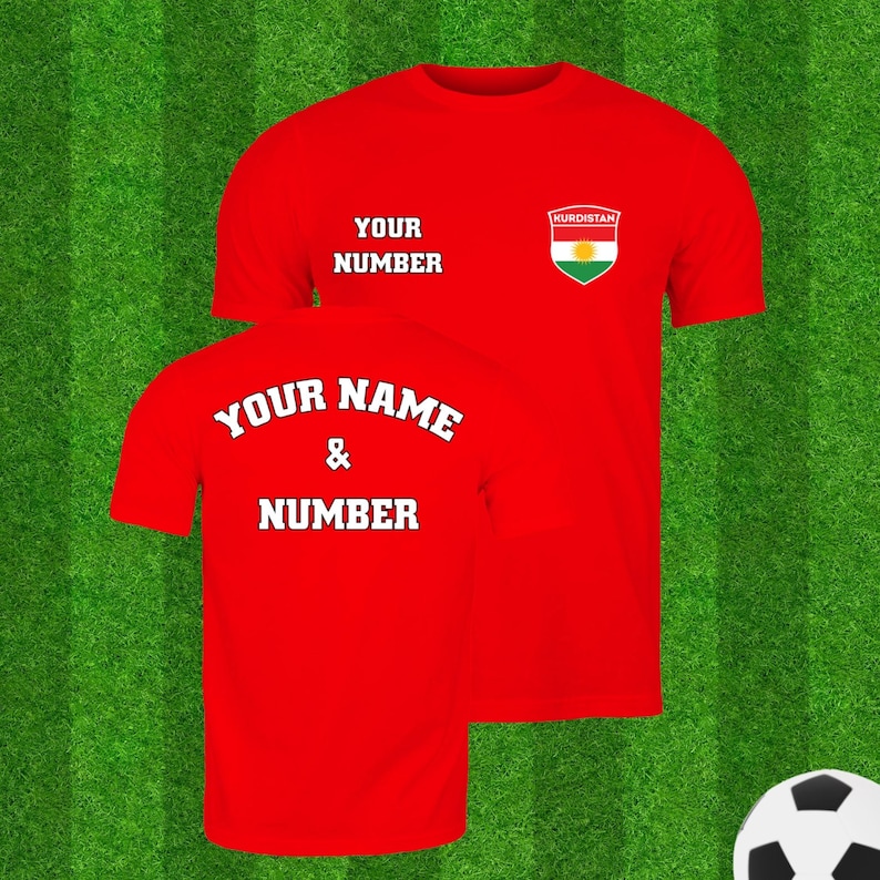 Puede incluir: Dos camisetas rojas con texto blanco sobre un fondo verde. La parte delantera de la camiseta tiene el texto "YOUR NUMBER" y un escudo con la palabra "KURDISTAN" y una bandera. La parte trasera de la camiseta tiene el texto "YOUR NAME & NUMBER". Hay un bal&oacute;n de f&uacute;tbol en la esquina.