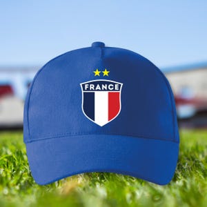 Peut inclure: Casquette de baseball bleue avec l'emblème de la France. La casquette présente un écusson avec le mot "FRANCE" et deux étoiles dorées. Fabriquée dans un matériau résistant, elle est idéale pour les activités de plein air.