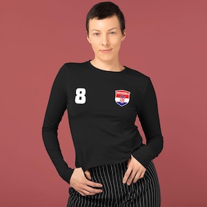 May include: Black long-sleeve shirt with the number 8 in white on the left chest. A Croatian coat of arms patch is on the right chest. The shirt is a solid black color.