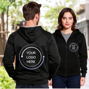 Könnte beinhalten: Schwarze Kapuzenpullover mit Reißverschluss und dem Text "YOUR LOGO HERE" in einem weißen Kreis. Die Kapuzenpullover haben eine Kapuze mit Kordelzug und werden über einem grauen T-Shirt und blauen Jeans getragen. Der Hintergrund ist verschwommen.