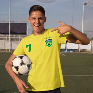 May include: A yellow t-shirt with a green number 7, a green and yellow Brazilian flag patch, and the word "BRASIL" in white letters. The shirt has five stars above the patch.