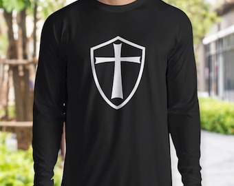 May include: Black long-sleeve shirt with a white shield and cross graphic. The shield has a pointed bottom and a rounded top.