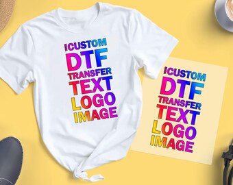 May include: A white t-shirt with a colourful design that says "Custom DTF Transfer Text Logo Image". The design is also on a separate sheet of paper.